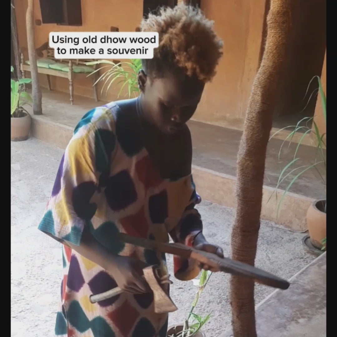 Hand- carving Dhow wood with an axe to make a unique wooden fish 